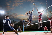 Two players jump in front of the net in a volleyball match.